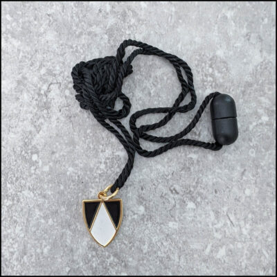 Black and white enameled gold-plated shield pendant on black adjustable cord